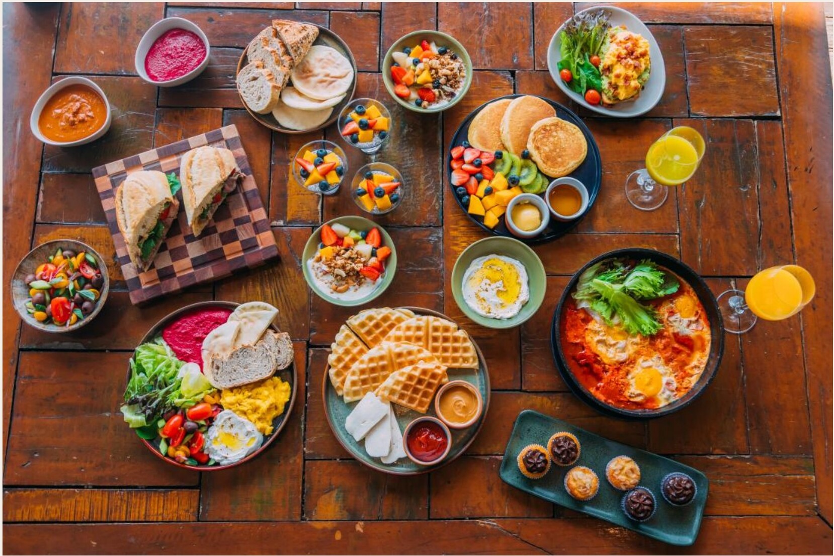 Mesa de madeira com diversos pratos de café da manhã